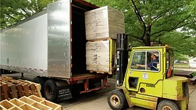 Front loader puts wooden pallets inside a semi truck