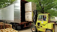 Front loader puts wooden pallets inside a semi truck