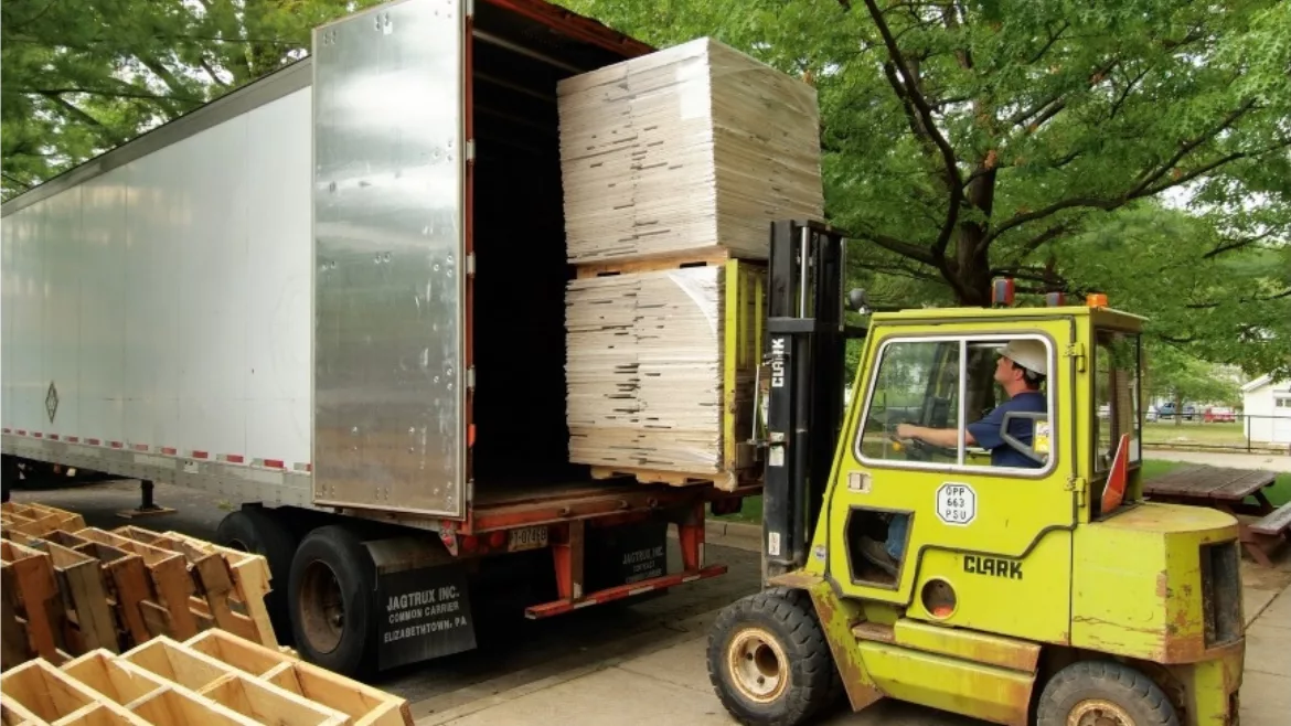 Front loader puts wooden pallets inside a semi truck