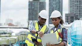 two construction workers use technology on the field