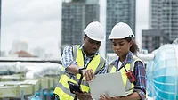 two construction workers use technology on the field