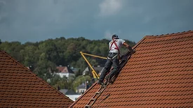 worker on a roof with shingles