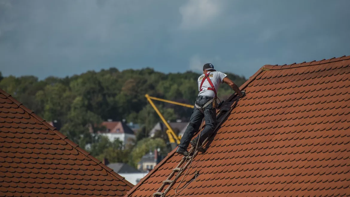 worker on a roof with shingles