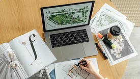 a person writing on white paper infront of a computer