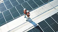 Two workers walk on rooftop solar