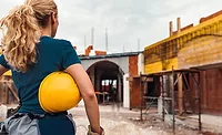 women in construction.png woman stands in front of construction site