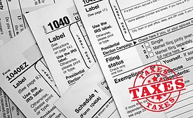 image shows tax paperwork with the word TAXES on top of them