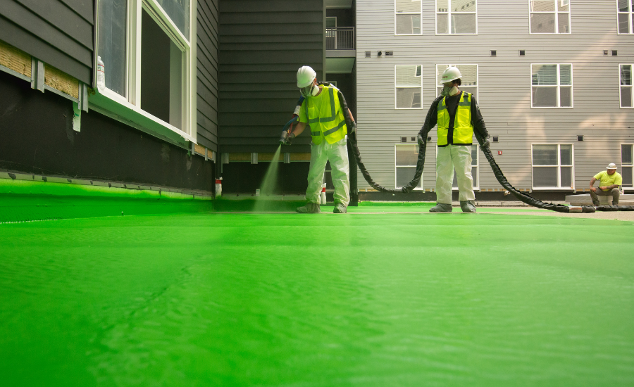 A construction crew waterproofs a plaza deck with Henry Prodeq, a polyurea-based membrane system that sets instantly. 