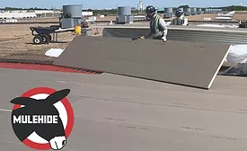 construction worker lays down roofing membrane
