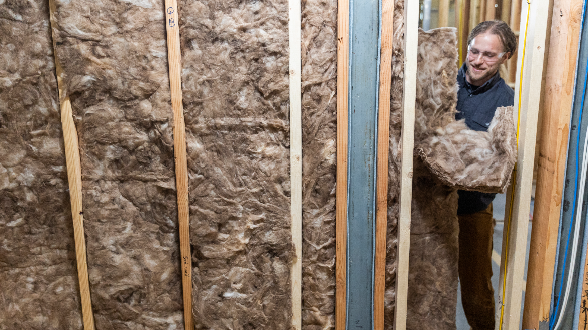 man in googles installs insulation into a wall system