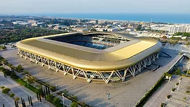 Aerial view of a modern stadium in an urban area, showcasing its unique architecture and surroundings.