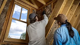woman and man install insulation into a home attic