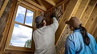 woman and man install insulation into a home attic