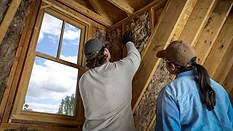 woman and man install insulation into a home attic