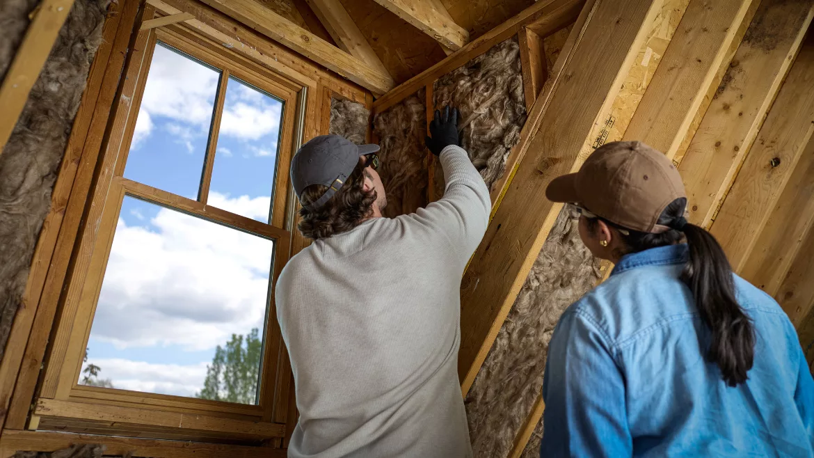 woman and man install insulation into a home attic