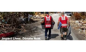 Two Red Cross workers walk in a disaster zone