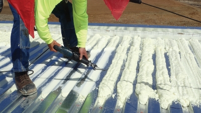 Shown is the installation of spray polyurethane foam in the flutes of a steel deck.